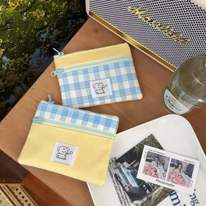 Detail of yellow and blue plaid canvas pouches featuring a cute cartoon dog logo label