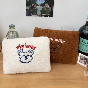 Close-up of white and brown sherpa pouches featuring cute bear embroidery and zipper