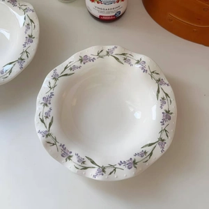 Detailed top view of scalloped lavender ceramic plate with floral motifs and wavy edges