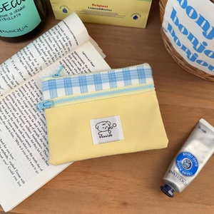 Close-up of yellow canvas storage pouch with blue checkered ribbon and cute puppy patch