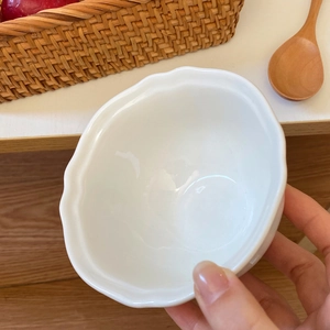 Ciotola minimalista in ceramica bianca con bordi a petalo in un ambiente domestico caldo