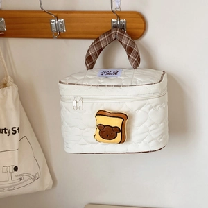 Dettaglio della borsa da trucco bianca trapuntata con manico a quadri marroni