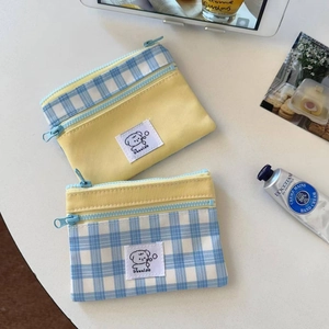 Detail of the dual zippers on the canvas pouch with yellow and blue checkered pattern