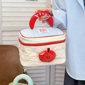 Quilted cartoon makeup bag with apple decor and red handle held by a model