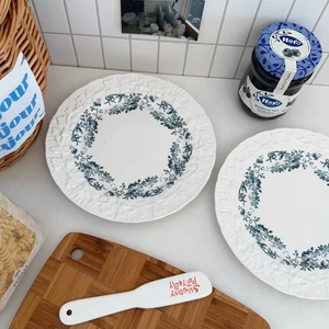 Close-up of white ceramic plate with blue floral pattern and embossed vintage edges