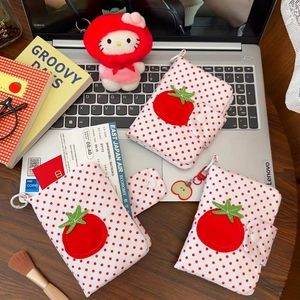 Détail de pochettes passeport en tissu à pois blancs avec motifs tomate et accessoires