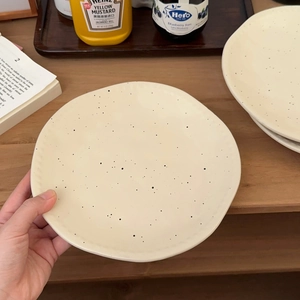 Detail of matte ink-splashed ceramic plate with irregular wavy edges for pasta or dessert
