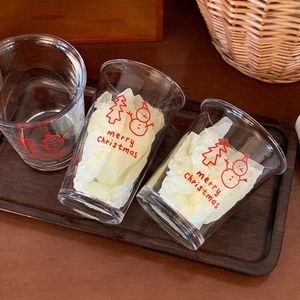 Detail of Christmas snowman glass set with red festive prints on a rustic wooden tray