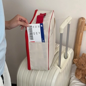 Travel storage bag for shoes with red zipper shown on white luggage handle