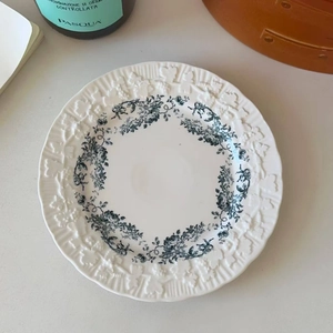 Close-up of white ceramic plate with blue floral pattern and embossed relief edges