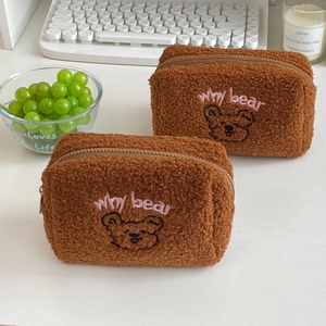 Close-up of two brown teddy fleece pouches with cute bear embroidery and metal zippers