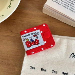 Close-up of red polka dot fabric cable organizer with a magnetic snap and cat tag