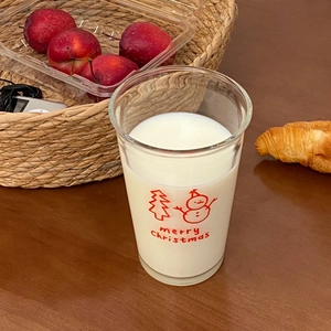Close-up of Christmas snowman glass cup filled with milk on a cozy breakfast table