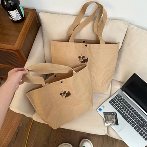 Detail of cartoon puppy kraft paper tote bags in two sizes on a cozy beige sofa