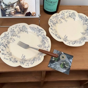 Detail of scalloped ceramic plate with blue floral and bird patterns on wooden table