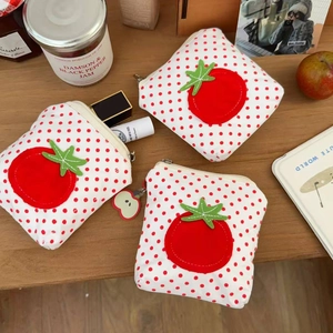 Gros plan de porte-monnaie tomates à pois rouges avec charme pomme sur bois