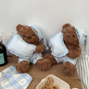 Detail of plush teddy bears in blue plaid pajamas holding pillows for sleep comfort