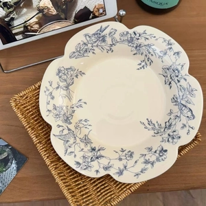 Detail of scalloped ceramic plate with blue vintage floral and bird pattern on placemat