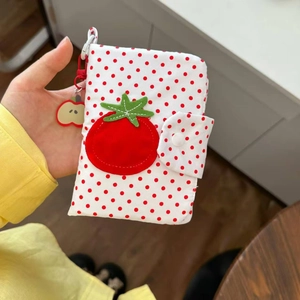 Détail du porte-passeport à pois rouges avec applique tomate et petit pendentif pomme