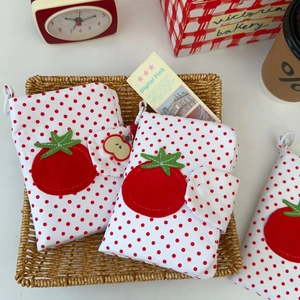 Gros plan détaillé du sac à passeport à pois tomate avec breloque éclair pomme