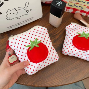 Détail de la pochette en toile à pois rouges avec écusson tomate et pendentif pomme