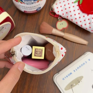 Mini porte-monnaie tomate à pois rouges avec breloque pomme sur bureau en bois