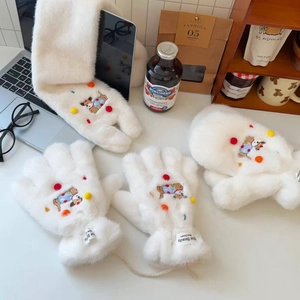 Detail of white faux fur mittens with dog embroidery and colorful pompom accents