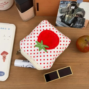 Mini porte-monnaie en toile à pois rouges avec applique tomate sur fond de bois