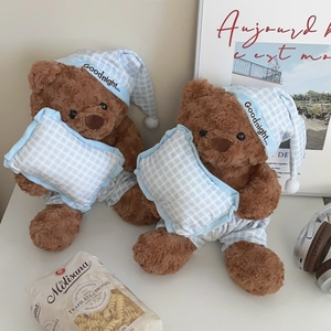 Detail of plush brown teddy bears in blue plaid pajamas and nightcaps on a desk