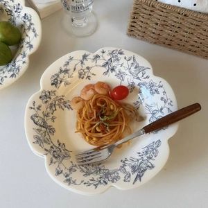 Macro detail of scalloped blue and white porcelain plate with floral and bird motifs
