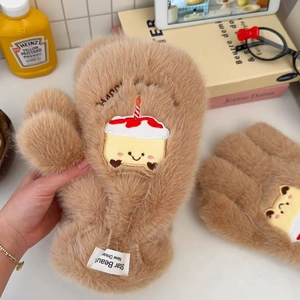 Close-up of brown plush mitten gloves featuring cute cake embroidery and brand woven label