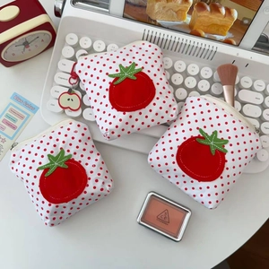 Gros plan d'un porte-monnaie tomate à pois rouges avec porte-clé pomme sur un bureau