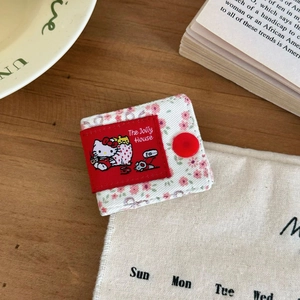 Close-up of floral fabric cable organizer with cute cat patch and red button detail