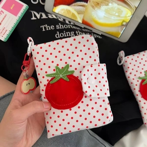 Détail du sac à passeport à pois tomate avec breloque pomme et mousqueton rouge