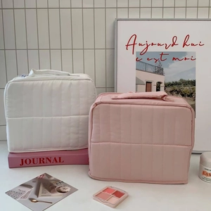 Quilted cosmetic bags in white and pink showing soft fabric texture and top handle