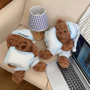 Detail of plush brown teddy bears in blue plaid pajamas with matching pillows on sofa