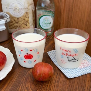 Detail of two cartoon dog and apple print glass cups on a dark wood table background