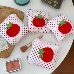 Vue à plat de porte-monnaie tomate à pois rouges sur table blanche avec accessoires