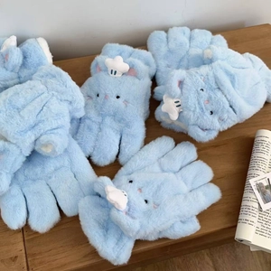 Detail of plush blue gloves with cat embroidery and star decor on a wooden desk
