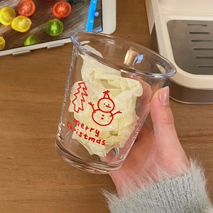 Close-up of hand holding a Christmas glass cup with snowman and merry christmas prints