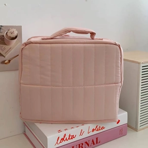 Detail of pink quilted makeup bag with vertical stitching and durable top handle