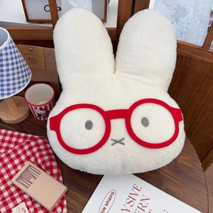 Close-up of cute plush bunny water bottle cover with red glasses on a cozy wooden table