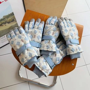 Detail of blue plaid ski gloves with cartoon bear prints and adjustable wrist straps