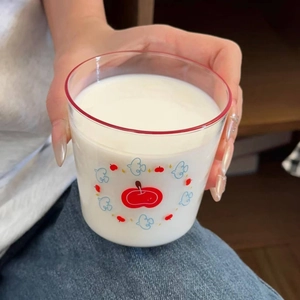 Detail of cute cartoon bird and apple prints on heat-resistant glass cup with red rim