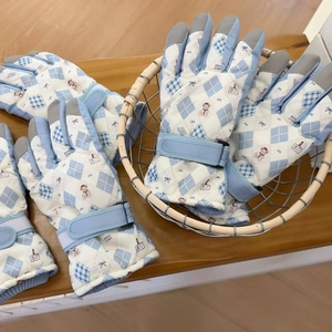 Detail of blue padded ski gloves with bear print and touchscreen fingertips in a basket