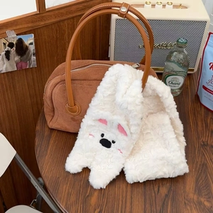Écharpe en peluche avec broderie et sac à main en daim marron sur une table en bois