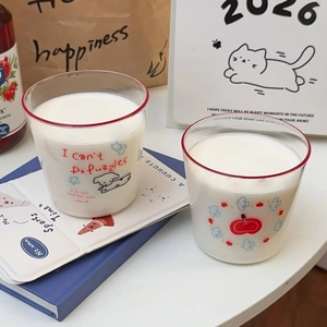 Cute cartoon puppy and apple glass cups with red rim, filled with milk on a cozy desk