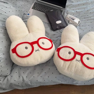 Cute white plush rabbit hot water bottle with red glasses on a cozy polka dot bedsheet