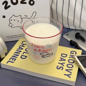 Close-up of cute cartoon dog glass cup with red rim on yellow book in a cozy setting