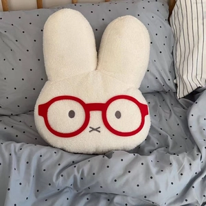 Close-up of white plush bunny hot water bottle cover with red round glasses detail